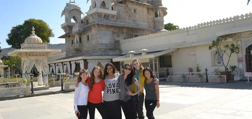 Group of friends posing for a photo at the scenic City Palace courtyard in Udaipur.