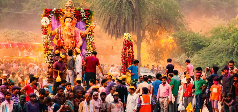 Crowd of devotees celebrating Ganesh Chaturthi festival with a large decorated deity idol.