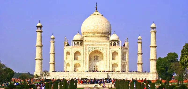 Full-frontal-view-of-the-magnificent-Taj-Mahal-under-a-clear-blue-sky-with-visitors-gathered-in-the-gardens