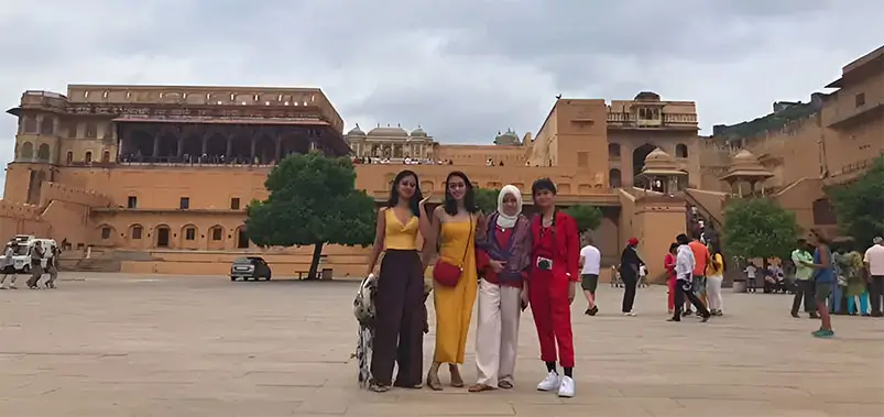 Group of tourists posing for a photo with a historic hilltop fort in the background