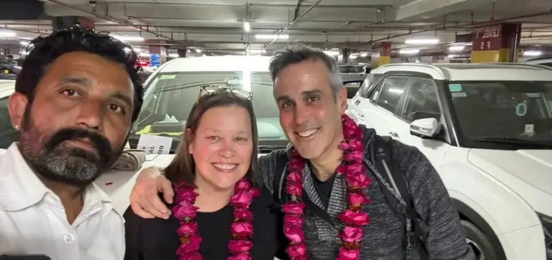 Travelers receiving traditional pink rose garlands from their private driver upon arrival